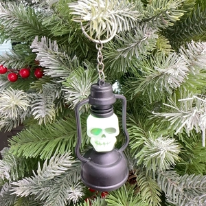 Close-up of a skull lantern keychain with green glowing light on a branch
