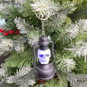Blue LED light up skull keychain lantern decoration hanging on green pine branch