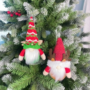 Close-up of Christmas gnomes with reindeer antlers and striped hats on a snowy tree