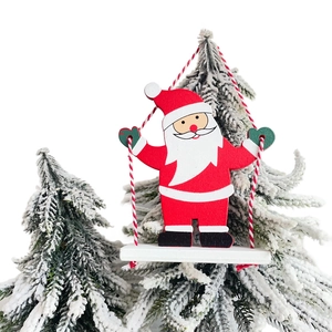 Dettaglio decorazione natalizia in legno Babbo Natale su altalena con pini innevati finti