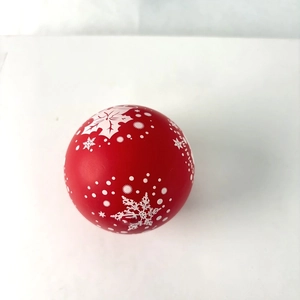 Close-up of a red Christmas ball with white snowflakes and Christmas text engraving