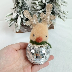Detail of a reflective disco ball Christmas deer ornament held by hand for scale