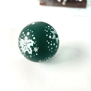 Detail of dark green Christmas ball ornament with white holly leaves and snowflake patterns