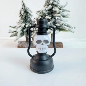 Detail of Halloween skeleton lantern keychain with black frame and metal ring on snowy background