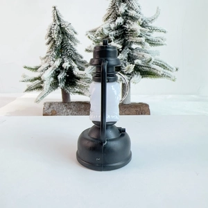 Miniature black vintage LED lantern with metal ring on festive pine branch background