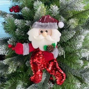 Close-up of Santa Claus hanging ornament with red sequins and pine cone on Christmas tree