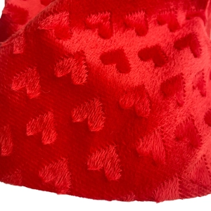 Macro detail of red plush velvet fabric with embossed heart patterns for Christmas hats