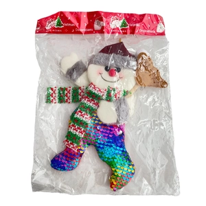 Detailed view of a plush snowman ornament with colorful sequins in its clear packaging