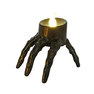 Detail of bronze skeleton hand candle holder with glowing LED candle for Halloween decor