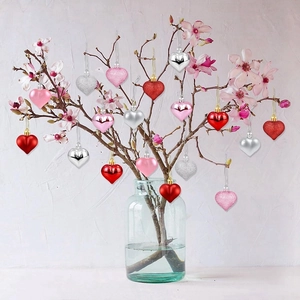 Macro shot of assorted red and pink heart ornaments hanging on cherry blossom branches
