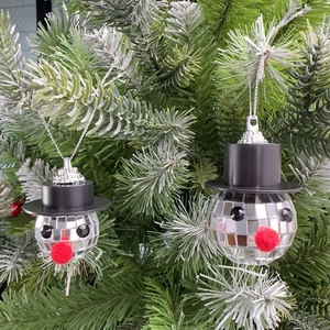 Close-up of disco ball snowman ornaments hanging on a green Christmas tree branch
