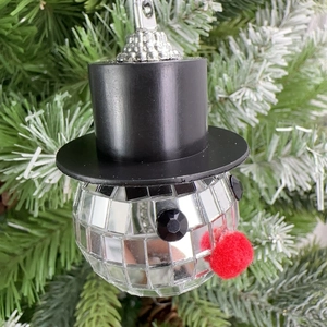 Close-up of disco ball snowman ornament with black top hat on a green Christmas tree