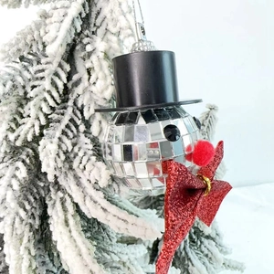 Mirror disco ball snowman ornament with top hat and red bow on a white Christmas tree