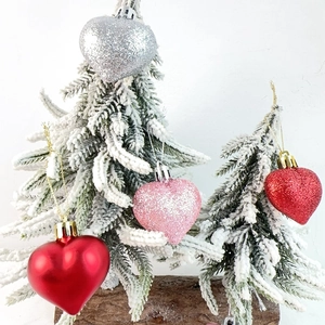 Detail of heart-shaped Christmas ornaments with glitter and matte finish on snow branch