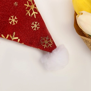 Close-up of red sequin fabric with golden snowflake patterns and a white plush pompom