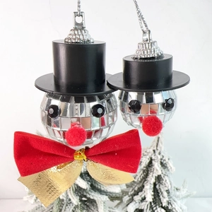 Close-up of disco ball snowman Christmas ornament with red bow and black top hat