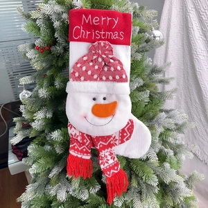 Knitted Christmas stocking with 3D snowman hanging on a snow-covered pine tree branch