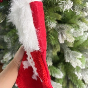 Classic red Christmas stocking with white plush trim held against a festive tree background