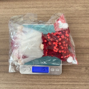 Detailed view of the 15.4g plush Christmas gnome ornament on a digital scale