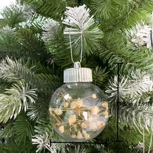 Pallina di Natale trasparente in PET con fiori secchi appesa a un ramo dell'albero