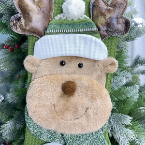Detailed close-up of a green knitted Christmas stocking with a 3D plush reindeer decoration
