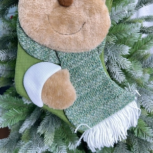 Detailed view of forest green knit Christmas stocking with 3D plush character and cotton tassels