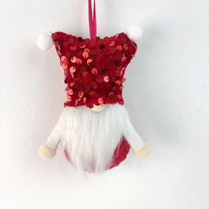 Detail of a Christmas gnome ornament with red sequins, white beard, and a hanging ribbon