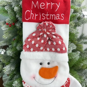 Close-up of a green knit Christmas stocking with a 3D snowman and embroidery