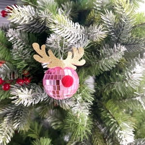 Pink disco ball reindeer ornament with gold glitter antlers hanging on a Christmas tree branch