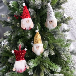 Christmas plush gnome ornaments with sequins and white beard hanging on a snowy tree