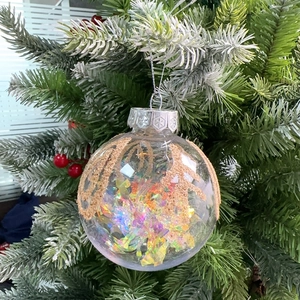 Detail of clear 8cm Christmas ball with gold glitter reindeer horns and colorful filling
