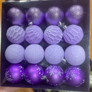 Détail de 16 boules de Noël violettes avec paillettes et motifs flocons dans une boîte