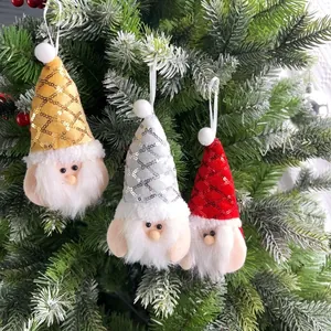 Close-up of three festive Christmas gnomes with sequins hats hanging on a green tree branch