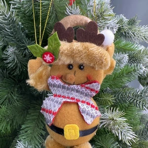 Close-up of reindeer plush ornament with plaid scarf hanging on a green Christmas tree