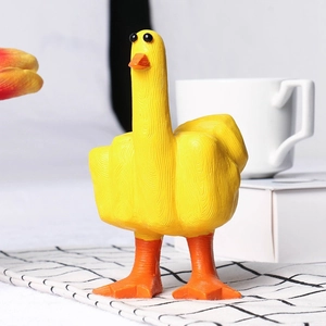 Gros plan d'une figurine canard en résine jaune faisant un doigt d'honneur amusant