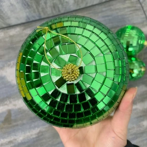 Close-up of a green mirror disco ball with reflective tiles and a golden hanging string