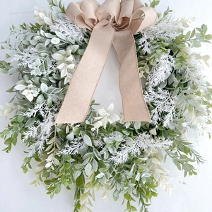 Close-up of faux greenery wreath with frosted leaves and a natural burlap bow decoration
