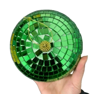 Green mosaic glass disco ball ornament with gold string hanging on white background