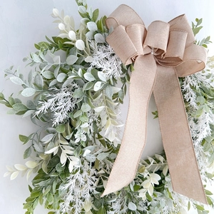 Detail of faux greenery wreath with eucalyptus leaves and large linen burlap bow decoration