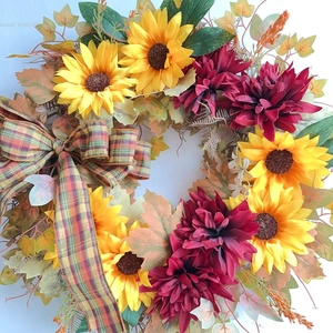 Close-up of autumn sunflower wreath with maple leaves and a plaid fabric bow