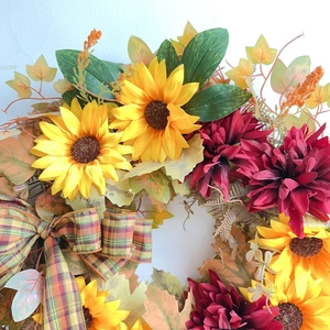 Detailed view of autumn wreath with sunflowers, red dahlias and plaid ribbon bow