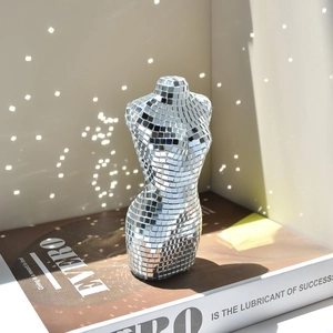 Statue torse féminin en miroir disco sur livre avec reflets scintillants décoratifs