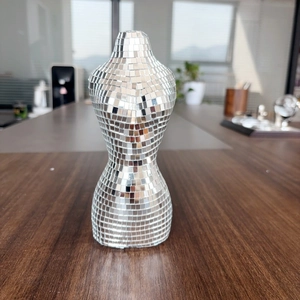 Détail d'une sculpture de torse féminin en miroir mosaïque disco sur une table en bois