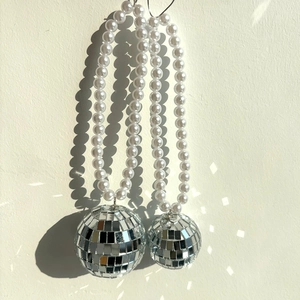 Détail de pendentifs boules à facettes disco avec chaînes décoratives en perles blanches