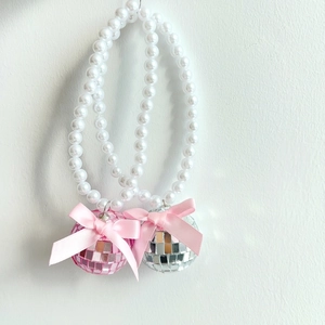 Détail de pendentifs boules disco avec perles et nœuds en satin rose pour voitures