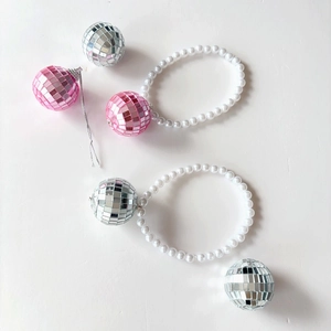 Détail de pendentifs boules disco roses et argentées avec perles blanches festives