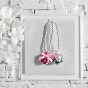 Détails de pendentifs boules disco avec nœuds roses et perles sur fond blanc pur