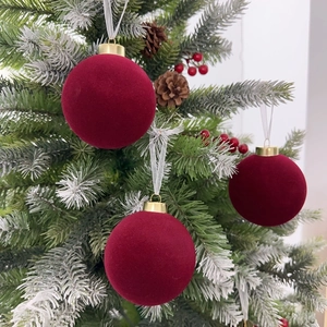Velvet burgundy Christmas ball ornaments with gold caps hanging on a festive tree branch