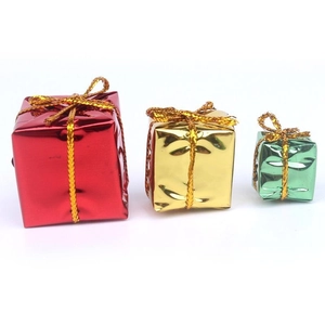 Three colorful Christmas gift box ornaments in red, gold, and green with golden strings