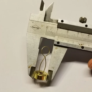 Golden metal ornament cap with spiral spring measured by a digital caliper tool